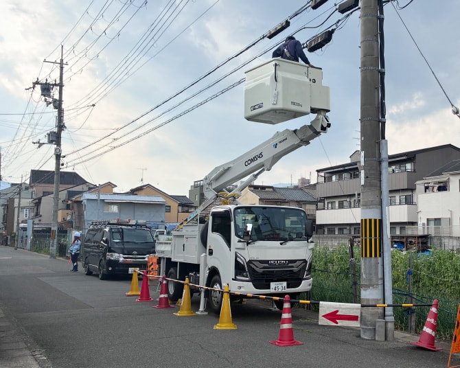 高所作業車を使用した、電柱および電線周りの電気通信工事の作業風景
