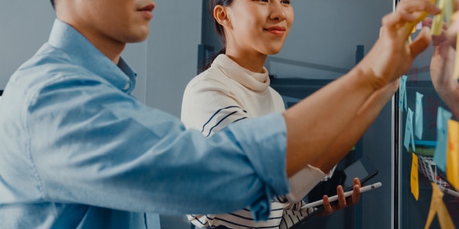 ボードに貼られた付箋を指差しながら、打ち合わせをする様子