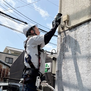 高所で外壁配線の作業をおこなう様子